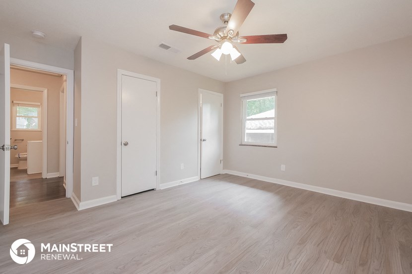 an empty living room with a ceiling fan and wood flooring