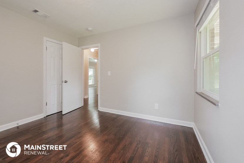 a living room with white walls and wood flooring and a white door
