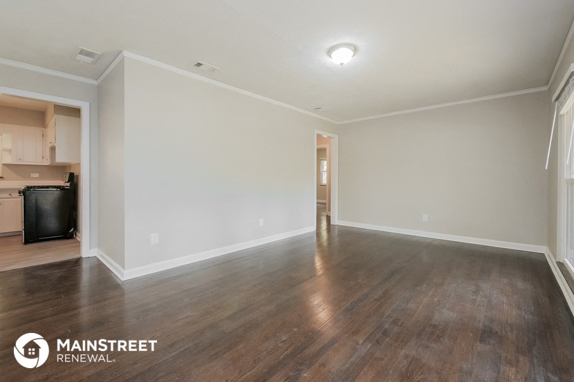 an empty living room with wood flooring and white walls