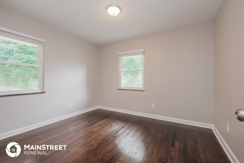 the upstairs bedroom with hardwood flooring and two windows