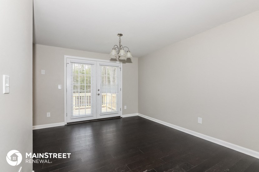 the living room of a home with dark wood flooring and a large white door