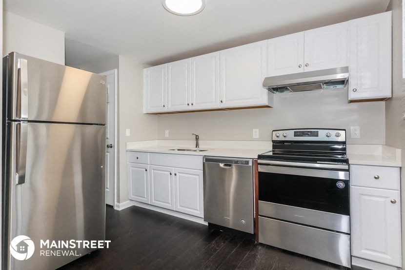 a white kitchen with stainless steel appliances and white cabinets