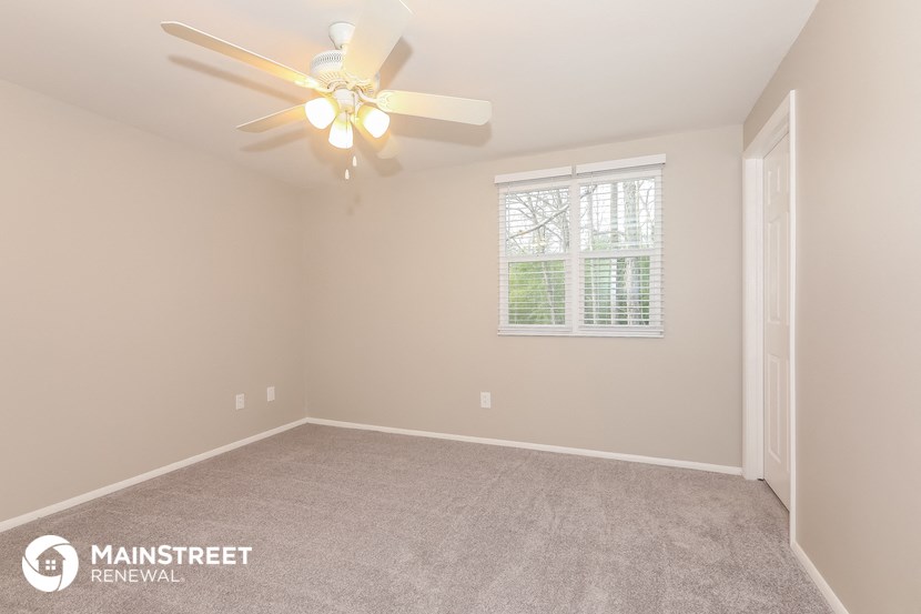 the spacious living room with ceiling fan and carpeting