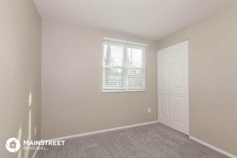 a bedroom with a door and a window and a carpeted floor
