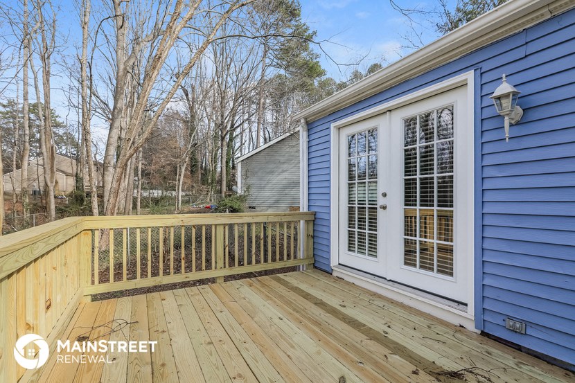 a backyard deck with a blue house and a white door