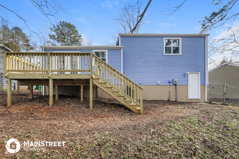 the back of a blue house with a wooden deck and a staircase