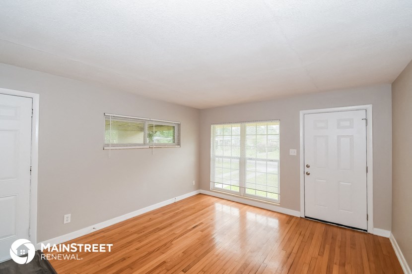 the living room of this home has a hardwood floor and a white door