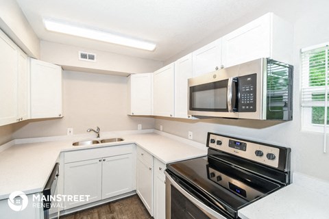 a kitchen with white cabinets and a stove and a microwave
