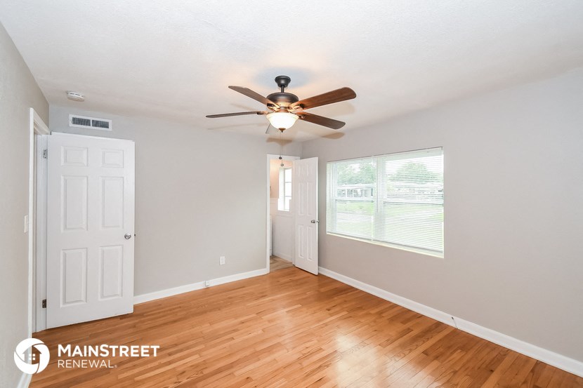 the living room and dining room with wood flooring and a ceiling fan