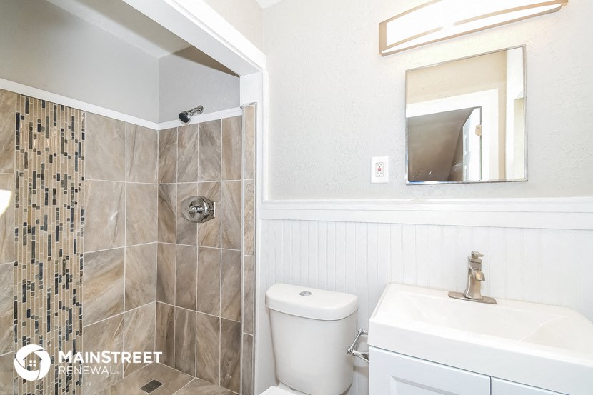 a bathroom with a toilet sink and shower and a mirror