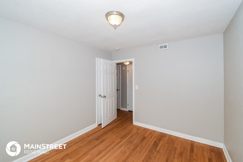 the living room of an apartment with wood floors and white walls