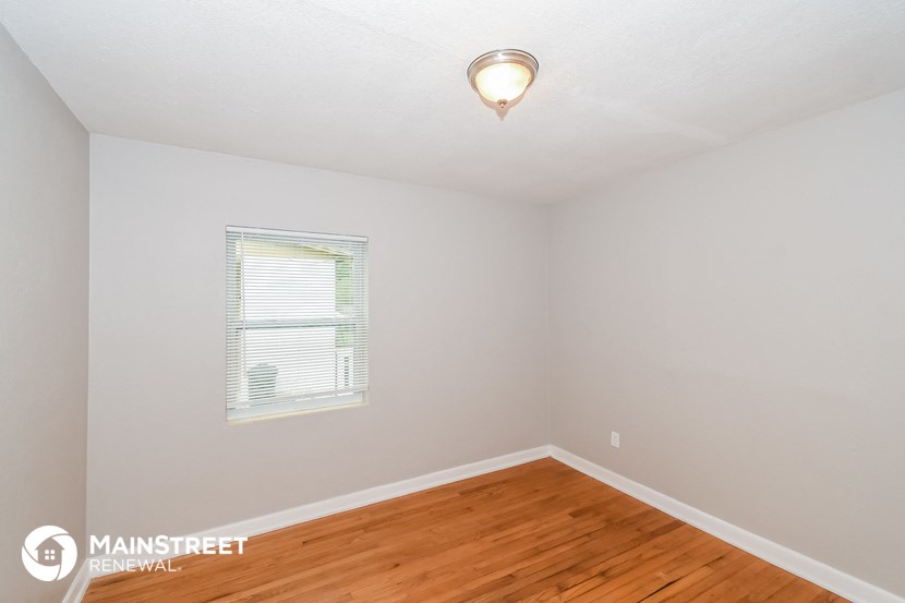 the bedroom of this house has a hardwood floor and a window
