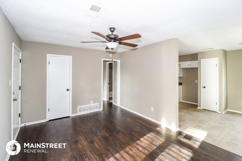an empty living room with wood floors and a ceiling fan