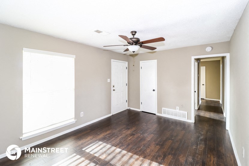 an empty living room with wood floors and a ceiling fan
