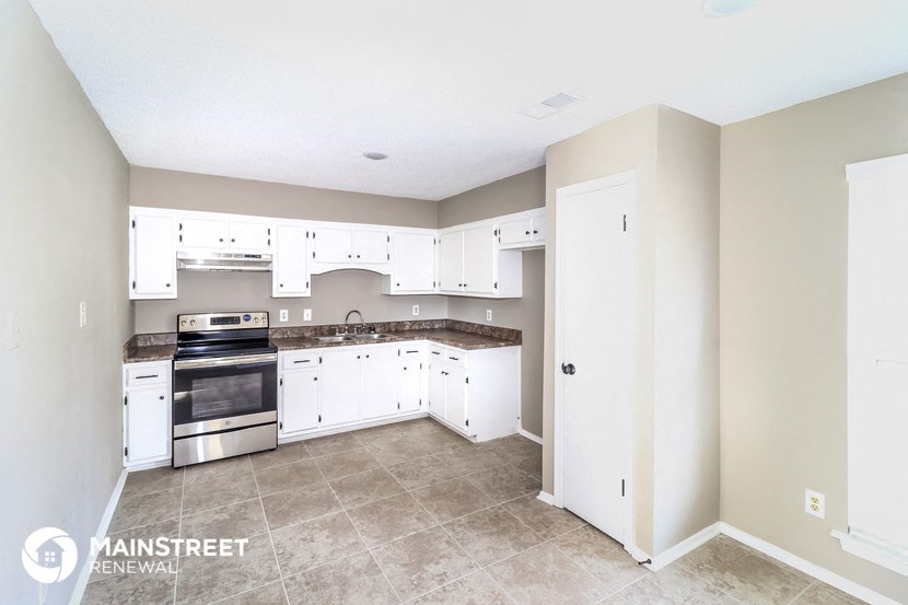 a kitchen with white cabinets and white appliances and tile floors