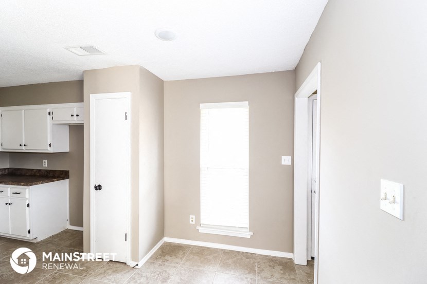 a kitchen with white cabinets and a door and a window