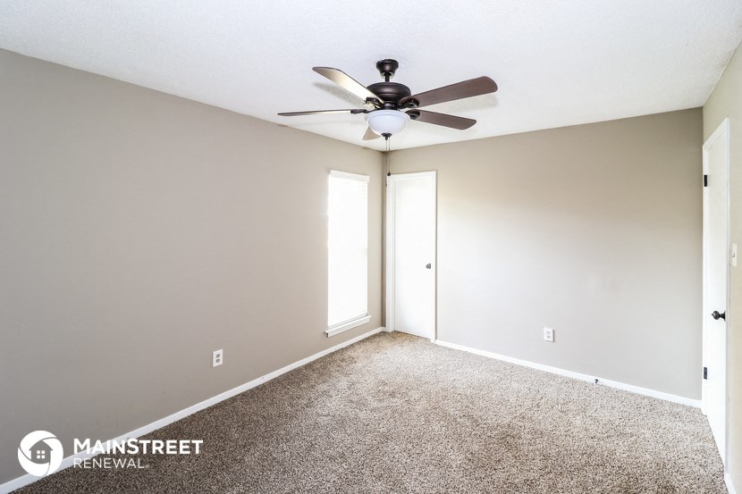 the spacious living room with ceiling fan and carpet