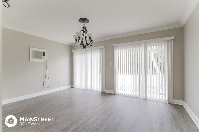 an empty living room with sliding glass doors and a chandelier