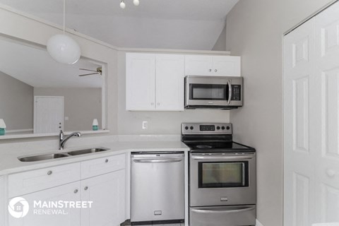 a white kitchen with stainless steel appliances and white cabinets