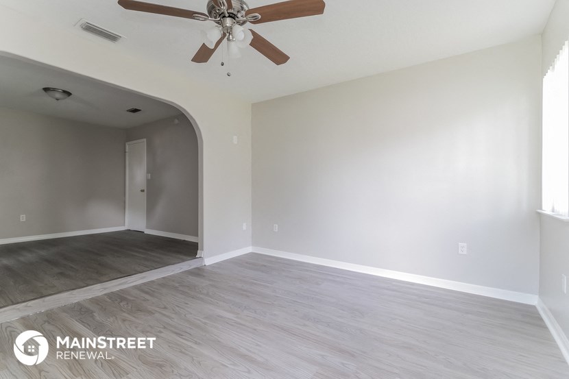 a living room with white walls and a ceiling fan