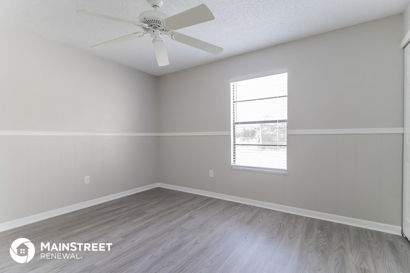 the spacious living room with ceiling fan and wood flooring