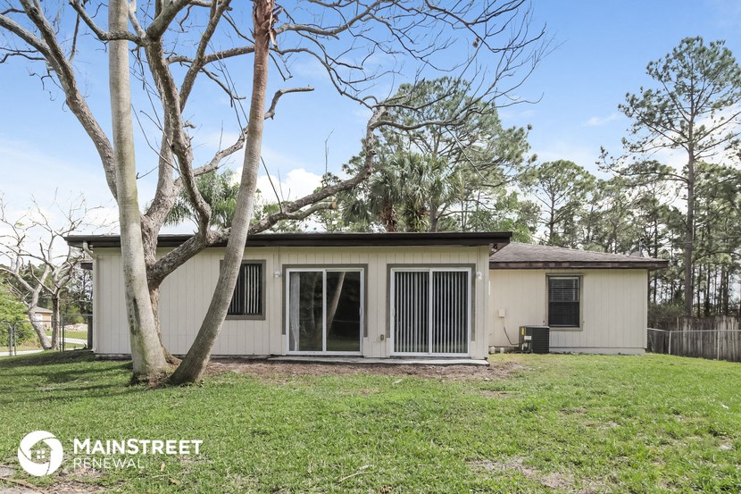 a small white house with a yard and some trees