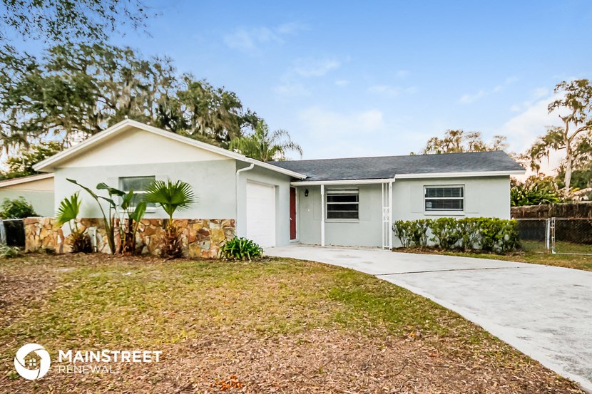 a white house with a driveway and palm trees