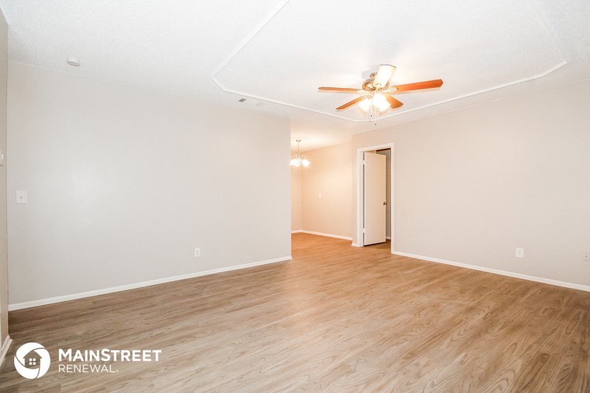 the spacious living room with wood flooring and ceiling fan