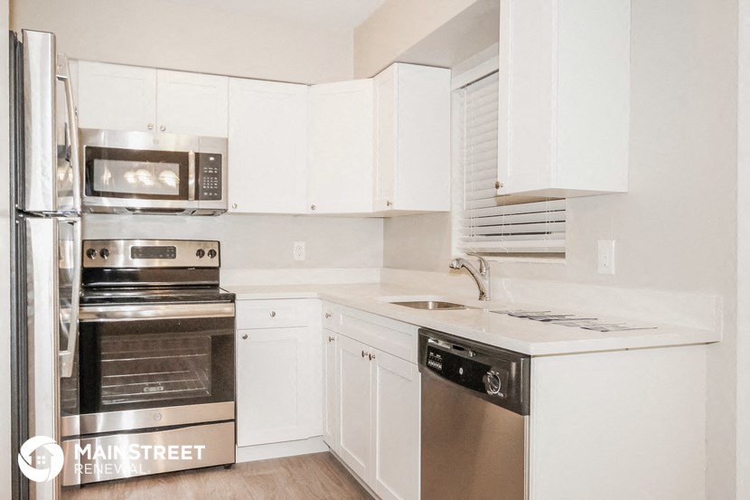 a white kitchen with stainless steel appliances and white cabinets