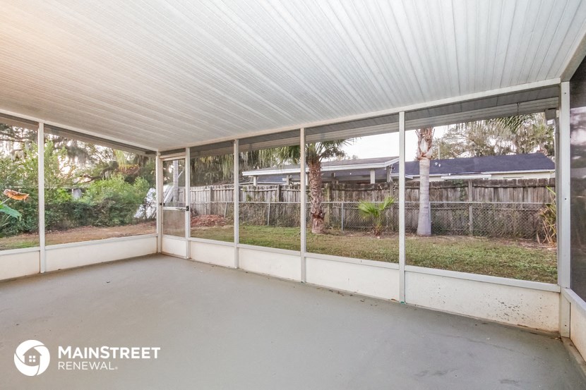 the screened porch has a view of the yard and the house
