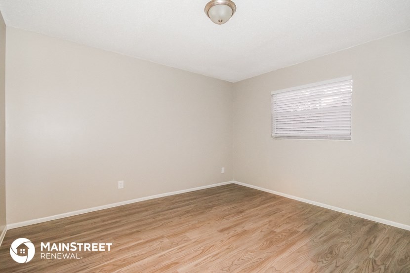 the spacious living room with wood flooring and white walls