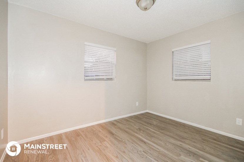 the living room of an apartment with wood floors and white walls