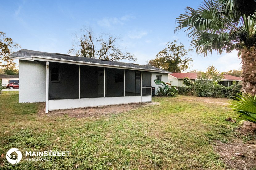 a small white house with a yard and a palm tree