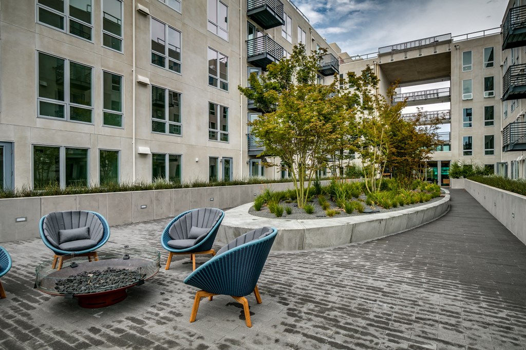 a courtyard with chairs and trees in front of a building