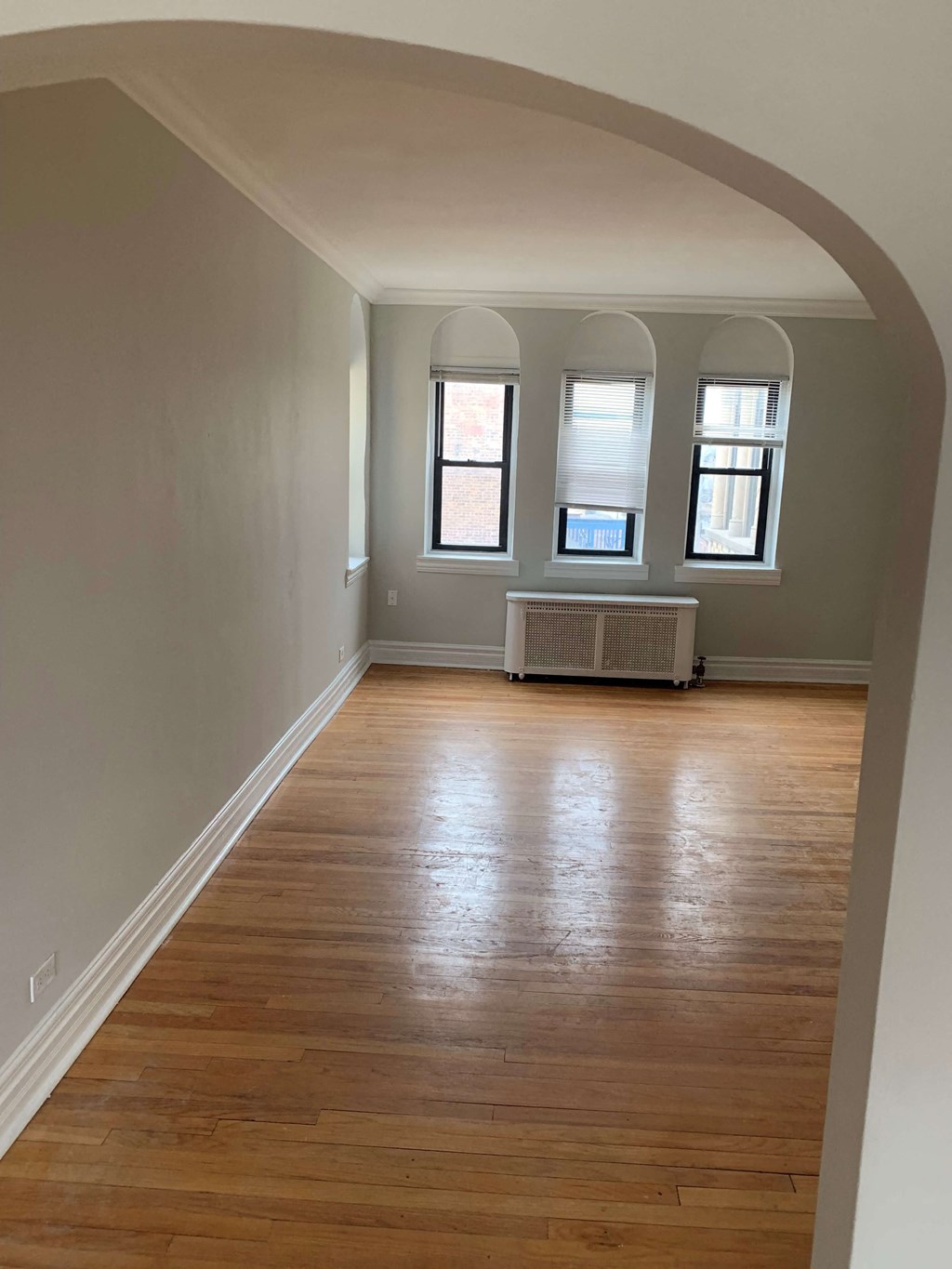 a living room with a hard wood floor and an arched doorway