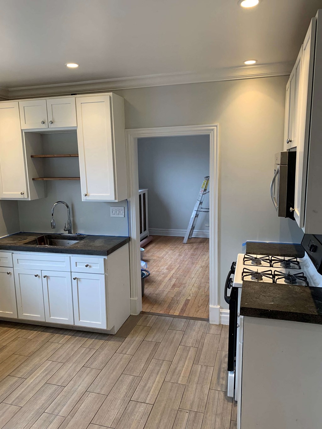 a kitchen with white cabinets and a wood floor
