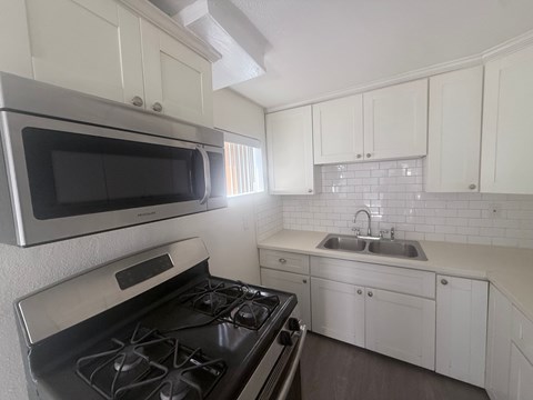 A kitchen with a black stove top oven and white cabinets.