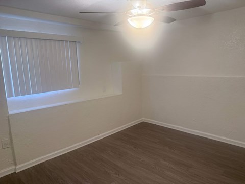 A room with a ceiling fan and a window with blinds.
