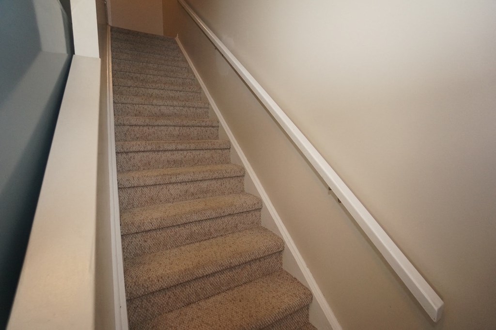 a carpeted staircase with a white railing and carpeted stairs with white walls