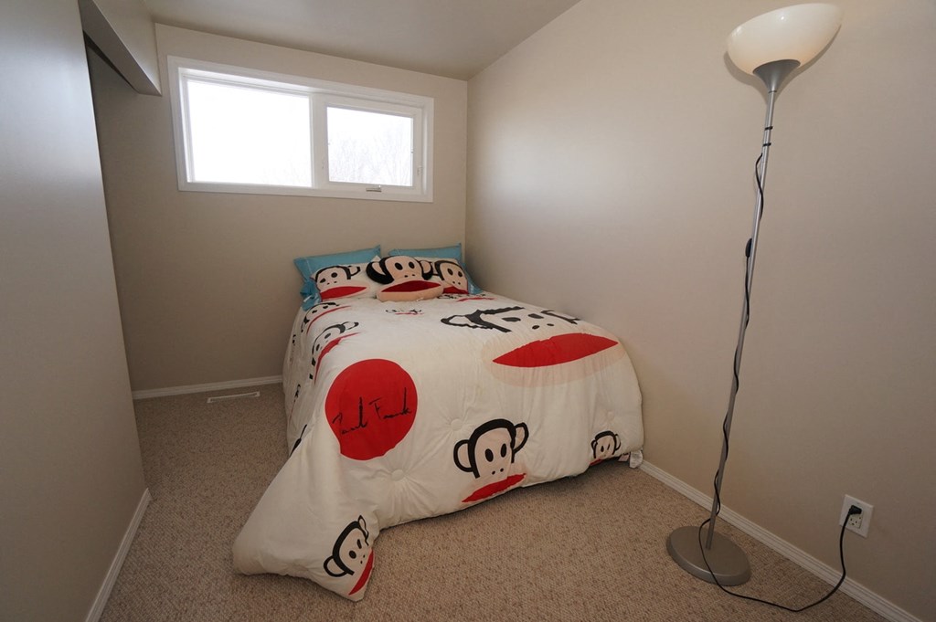 a bedroom with a bed and a lamp and a window