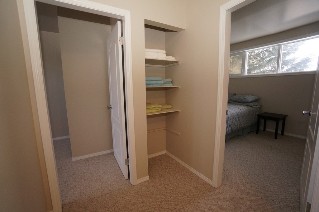 a bedroom with a closet with shelves and a window