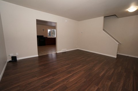 an empty living room with hard wood floors and white walls