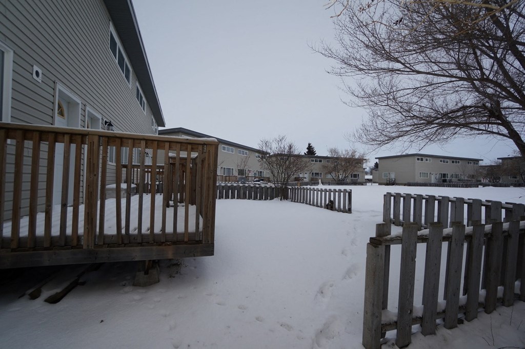a yard covered in snow with a wooden fence