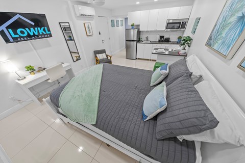 a bedroom with a bed and a kitchen in the background