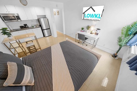 a bedroom with a bed and a kitchen in the background