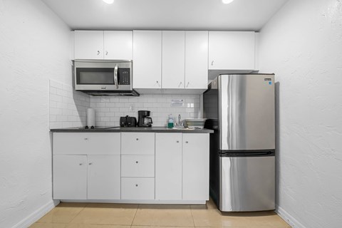 a kitchen with white cabinets and a stainless steel refrigerator