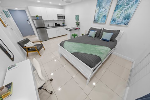 a bedroom with a bed and a kitchen in the background