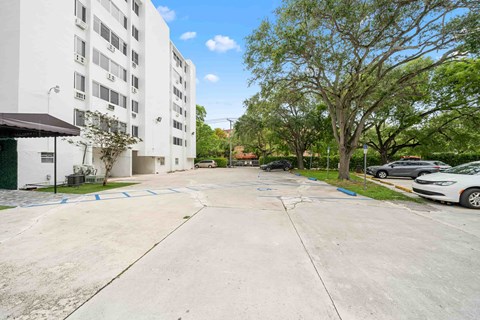 an empty parking lot with a white building on the side of it