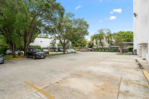 a parking lot with cars and trees in front of a building