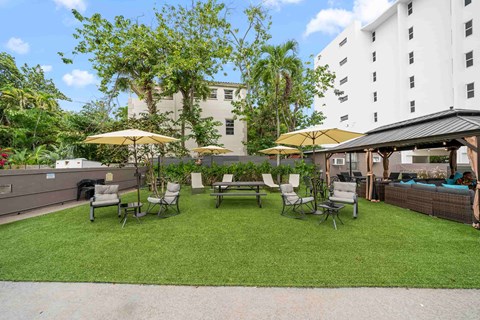 a backyard patio with tables and chairs and umbrellas